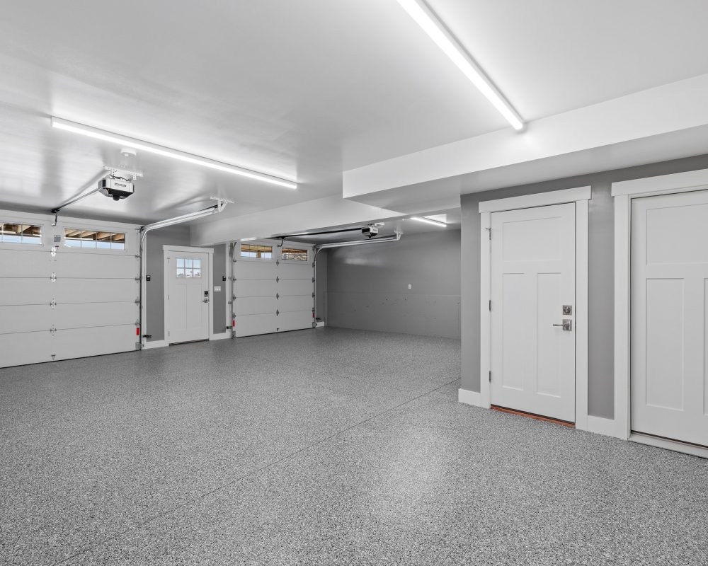 Interior view of an empty garage with a metallic surface floor and lighting