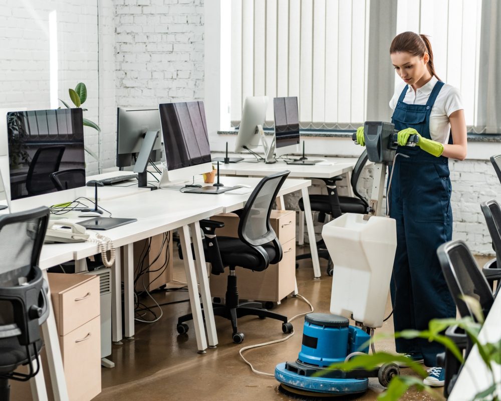 young cleaner washing floor in open space office with cleaning machine
